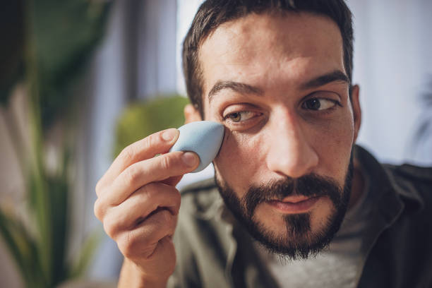 Man using a handheld facial massage tool near his eye