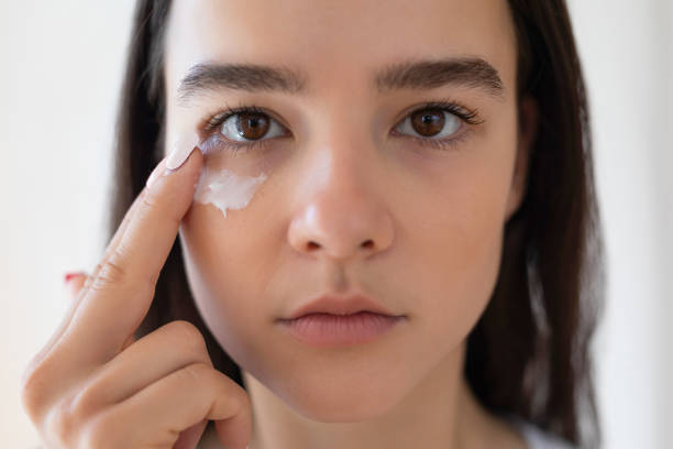 Woman applying cream under her eye